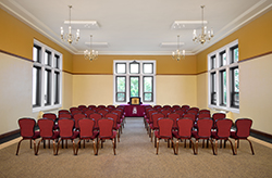 A view of another MSU Union meeting space filled with maroon upholstered chairs in two columns of five chairs in multiple rows, with windos to the left right and front.